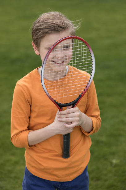 istock Adorable smiling little boy looking through badminton racquet 802480690