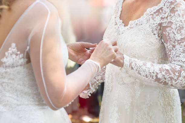 Same sex gay lesbian bride places ring on finger during wedding ceremony stock photo