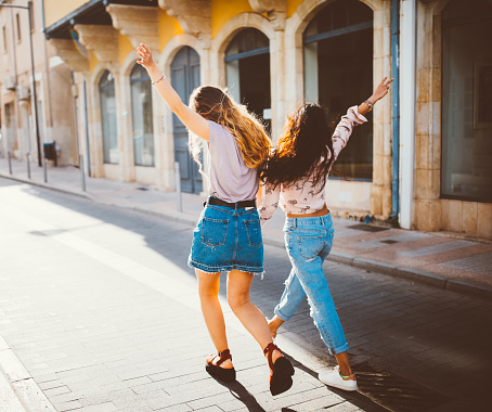Beautiful teenage hipster girls on Spanish holidays walking and having fun in antique city streets
