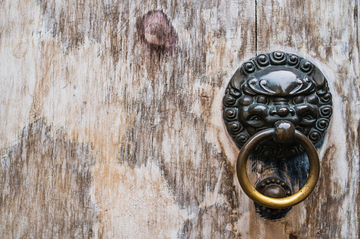 Bronze ancient knocker against old wooden door