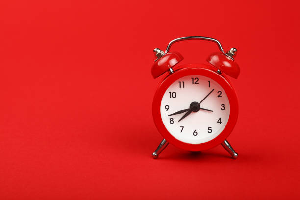 One red alarm clock over red background close up