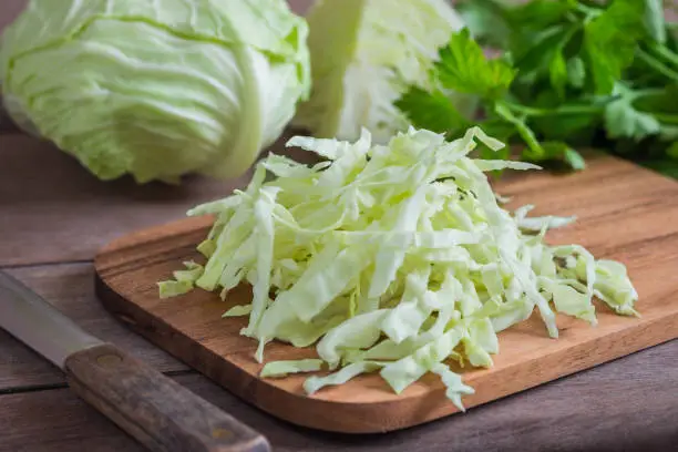 Photo of Fresh shredded cabbage on wooden cutting board