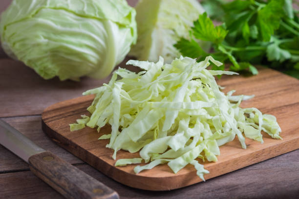 fresh shredded cabbage on wooden cutting board - head cabbage imagens e fotografias de stock