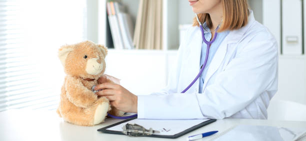 istock Female doctor examining a Teddy bear  patient by stethoscope 802545554