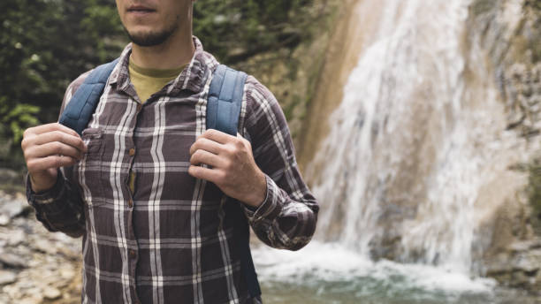 istock Traveler Explorer Hands Holds Backpack Strap On Waterfall Background Hiking Journey Travel Trek Concept 802545574