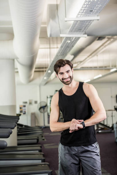 istock Smiling man on treadmill looking at smartwatch 802582216