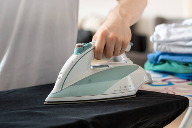 istock An iron on an ironing board with a black shirt close up from the side 802592830