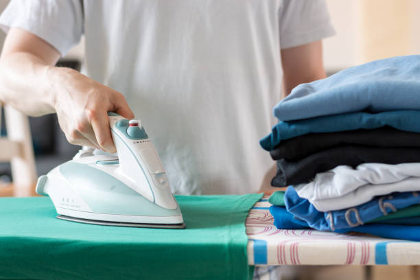 istock An iron on an ironing board with a green shirt close up from the side 802592900