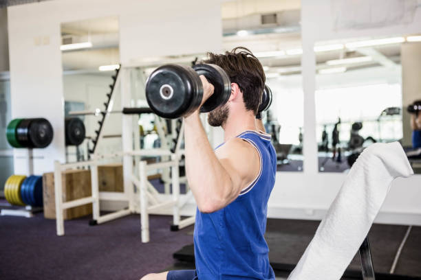 istock Muscular man lifting dumbbells on bench 802602008