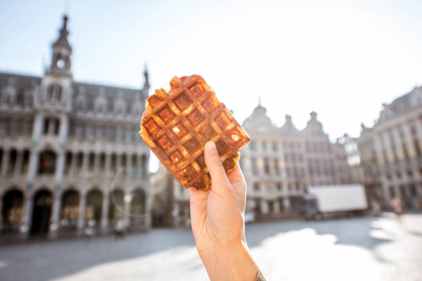 Holding belgian waffle outdoors Holding a traditional belgian waffle on the central square background with city hall in Brussels. Belgian food concept city of brussels stock pictures, royalty-free photos & images