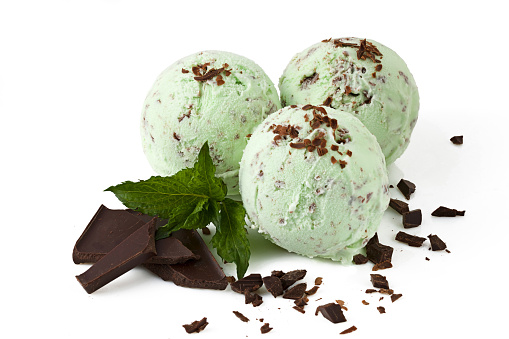 Mint ice cream with chocolate crumbs. Three scoops of ice cream with green mint taste and chocolate crumbs, decorated with chocolate crumbs and sprig of mint on a white background isolated with clipping path. Closeup view.