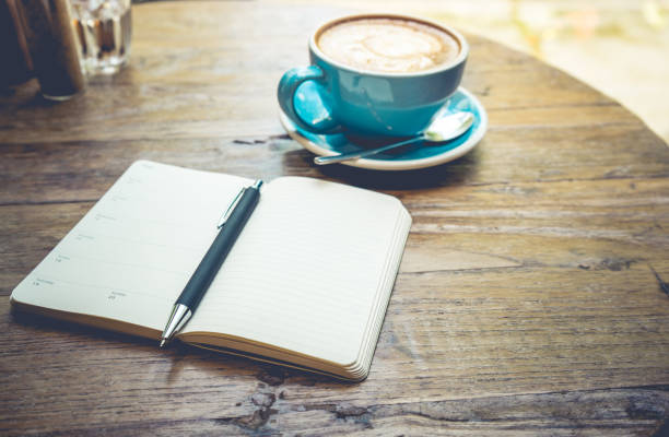 istock Cup of coffee latte with notepad on wooden table 802649328