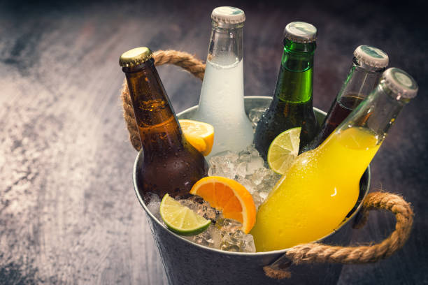 koude flessen van diverse drankjes in de ijsemmer - koude dranken stockfoto's en -beelden