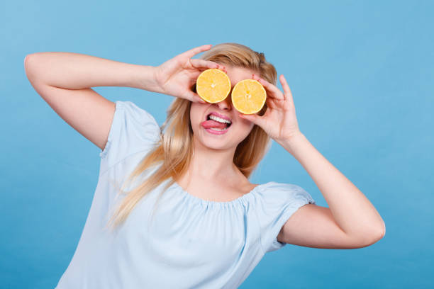 istock Woman holding fruit lemon half on eyes 802667746