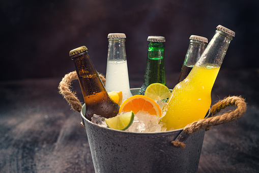 Cold bottles of various drinks in the bucket with ice