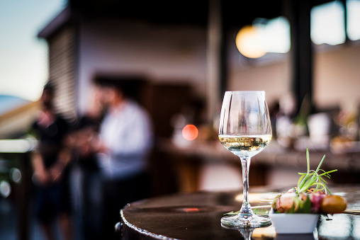 vaso de vino blanco con refrigerios de tapa de comida gourmet en el bar al aire libre al atardecer photo