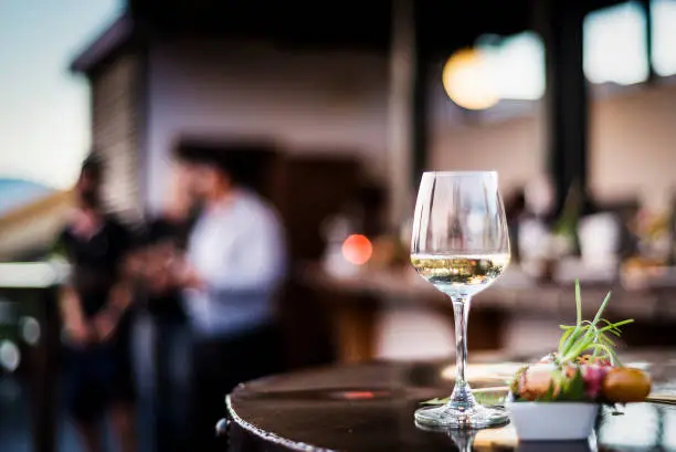 glass of white wine with gourmet food tapa snacks in outdoors bar at sunset