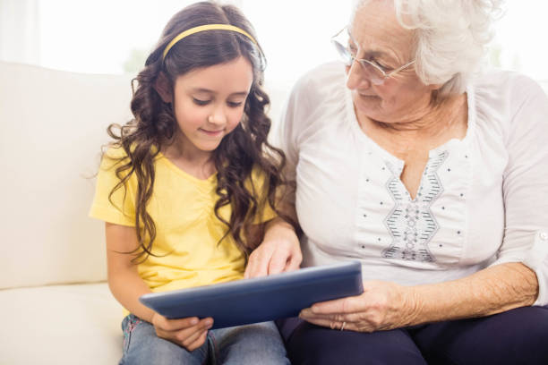 istock Concentrated granddaughter using tablet with grandmother 802674766