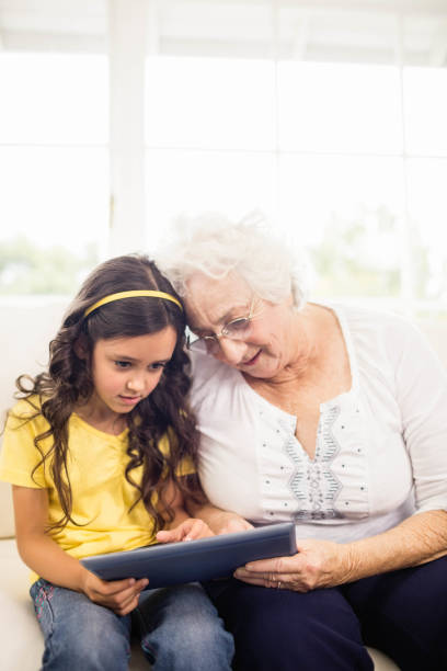 istock Concentrated granddaughter using tablet with grandmother 802674772