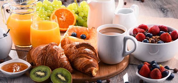 Sweet breakfast of croissant and honey. Coffee, orange juice and fruits