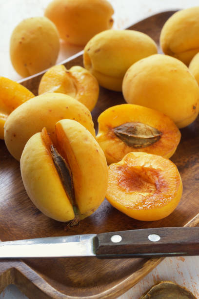istock Whole and cut apricots on a wooden platter 802693374
