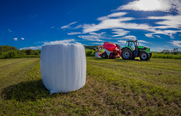 трактор с силосным тюков машины - silage field hay cultivated land стоковые фото и изображения