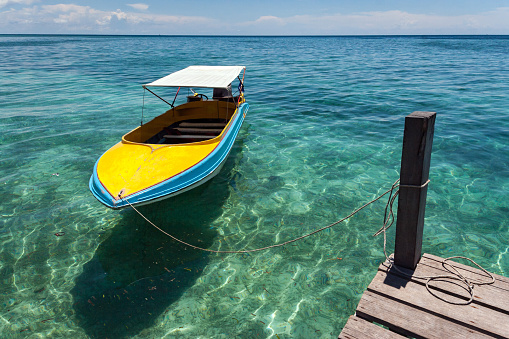 SIPADAN, BORNEO, MALAYSIA - APRIL 25, 2009: Colorful boat floating in calm crystal clear water.