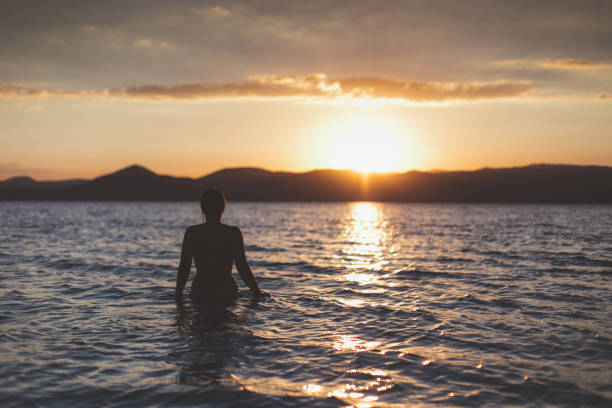 istock Woman relaxing in the water at sunset. 802763394