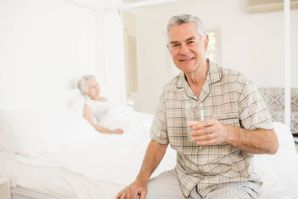 peaceful senior man holding glass of water - quilt 60s 70s activity imagens e fotografias de stock