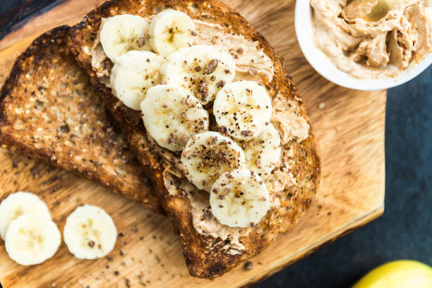 torradas de trigo integral semearam de pão com manteiga de amendoim e banan - healthy eating pasta flour food - fotografias e filmes do acervo