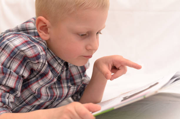 istock A five-year-old boy is reading a book on the bed. 802772690