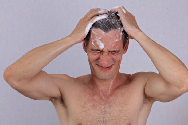 Man washing his hair, shampoo soap eye burn, irritation