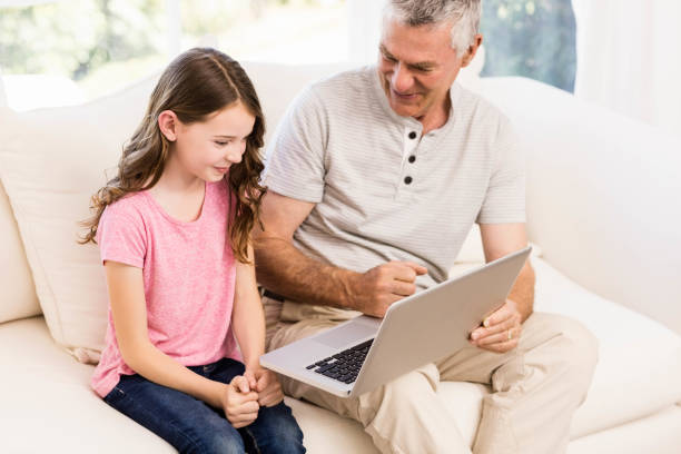 istock Smiling grandfather and granddaughter using laptop 802778122