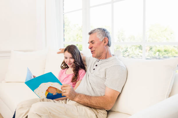 istock Smiling grandfather and granddaughter reading book 802778138