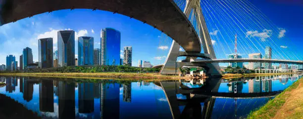 Panoramic shot of São Paulo skyline around the cable stayed bridge with modern office buildings in the background. Reflections in the River Pinheiros.