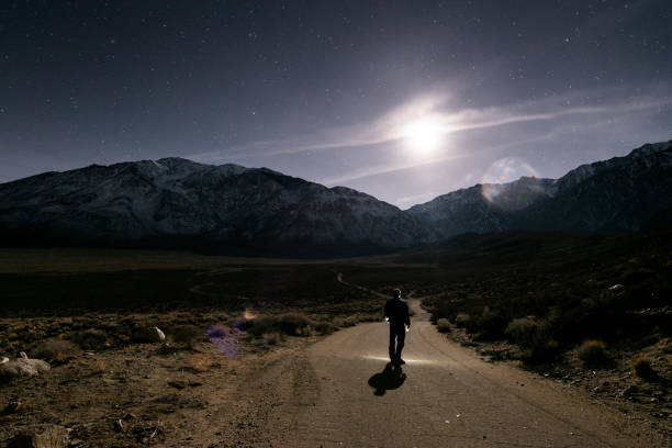 istock Man walking in mountains at night under moon 802798940