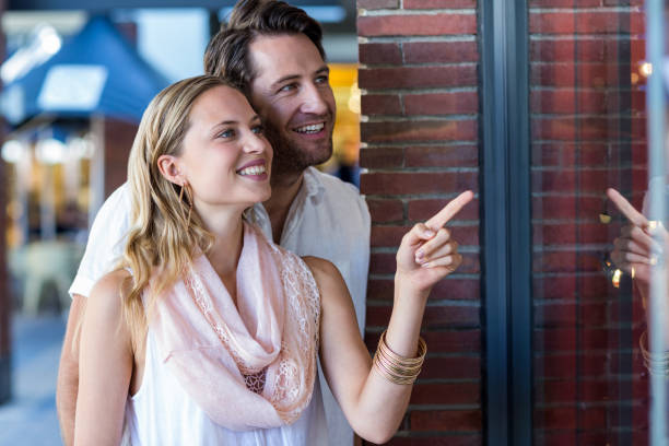 istock Smiling couple going window shopping and pointing at window 802799114