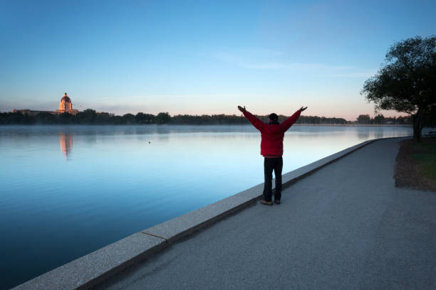 passeggiando per il lago wascana con l'edificio delle gambere regina saskatchewan nel retro - saskatchewan regina parliament building wascana lake foto e immagini stock