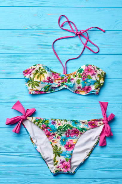 istock Flowery swimsuit, wooden background. 802852304