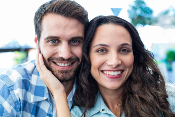 istock Cute couple sitting outside a cafe smiling at camera 802857434