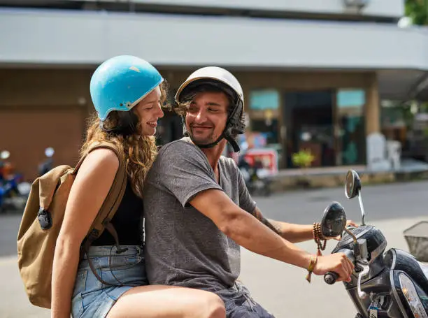 Shot of two happy backpackers riding a motorcycle through a foreign city