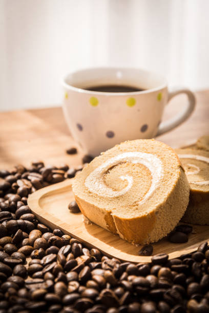 Roll coffee cake and coffee bean with wooden table and window light