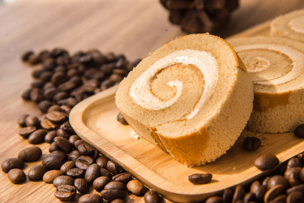 Roll coffee cake and coffee bean with wooden table and window light