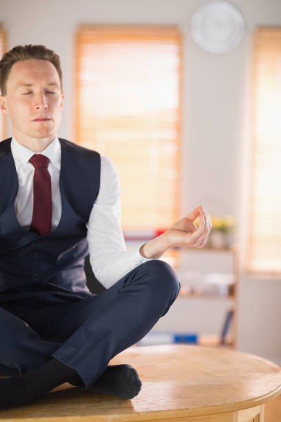 istock Calm businessman meditating in lotus pose 802885834