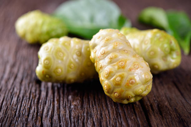 istock whole fresh noni fruit with leaf on wooden table 802896242