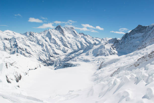 Snow capped mountain view of Swiss Alps at Jungfrau, Switzerland Base of a mountain covered in snow light up in the bright sun. Jungfrau is the Top of Europe and destination for tourists coming to Switzerland top of ski mountain stock pictures, royalty-free photos & images