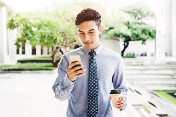 Friendly Businessman Smile with smart phone outdoor, Lifestyle of modern male to communicate or use technology in business, Always connected concept