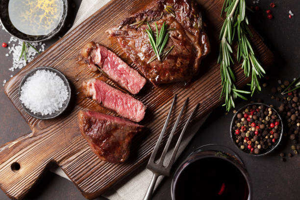 Grilled ribeye beef steak with red wine, herbs and spices Grilled ribeye beef steak with red wine, herbs and spices. Top view fork silverware table knife fine dining stock pictures, royalty-free photos & images