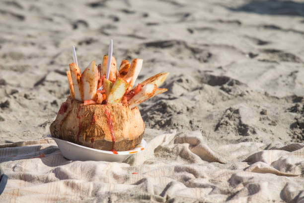 Coconut with fruit and spicy chili on the beach of Rosarito, Baja California. Mexico