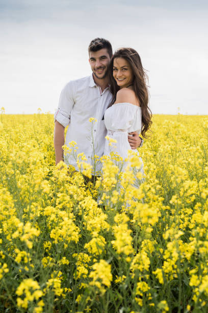 istock Happy couple standing embraced among spring yellow flowers. 802923808